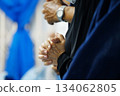 Close-up of a believer clasping their hands in prayer during worship. Soft lighting and added film grain create a classic, emotional atmosphere. Suitable for themes of faith, spirituality, devotion 134062805