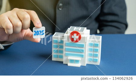 2025 in the hands of a man near the hospital building. Medical planning and forecasting for the year 2025, strategy, and development in the healthcare sector. Medicine plan concept 134062926