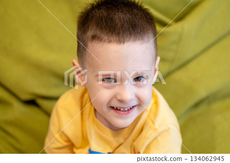 Happy toddler boy 3 or 4 years old smiles while looking at the camera indoor. Childhood and lifestyle concept. Portrait photo, close-up 134062945