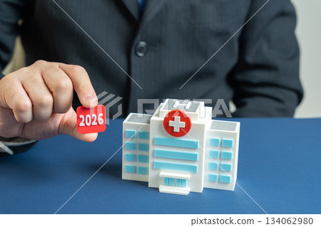2026 in the hands of a man near the hospital building. Medical planning and forecasting for the year 2026, strategy, and development in the healthcare sector. Medicine plan concept 134062980