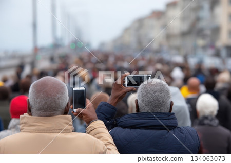 Crowd of urban people using mobile phones at a busy outdoor event in a coastal city setting 134063073