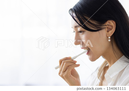 窗外光線灑在一位正在刷牙的女士身上，鏡頭特寫。 134063111