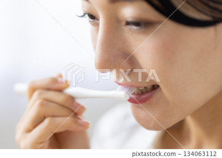 窗外光線灑在一位正在刷牙的女士身上，鏡頭特寫。 134063112