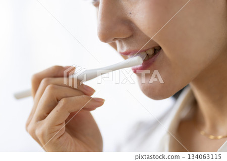 窗外光線灑在一位正在刷牙的女士身上，鏡頭特寫。 134063115