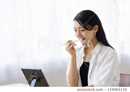 一位女士在窗邊對著鏡子刷牙。 134063116