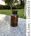 Amber glass bottle on stone table outdoors 134064576