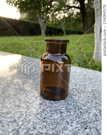 Amber glass bottle on stone table outdoors Amber glass bottle on stone table outdoors 134064576