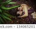 Couple peacefully embracing on cozy carpet adorned with fairy lights in a tranquil indoor space 134065201