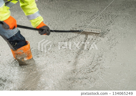Worker Smoothing Fresh Concrete Surface with Tool for Leveling and Finishing, Construction 134065249