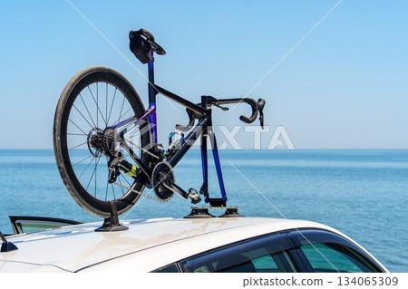 Road Bike Secured on Car Roof Rack for Transportation Near the Ocean, Sunny Day 134065309