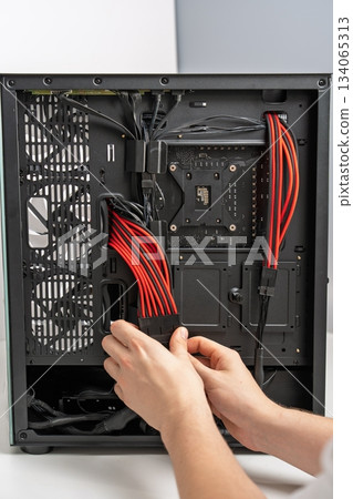 Computer Assembly Connecting Power Supply Cables inside PC Case for Optimal Performance Computer Assembly Connecting Power Supply Cables inside PC Case for Optimal Performance 134065313