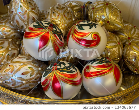 Red and gold patterned Christmas baubles arranged in decorative bowl display. Festive elegance, traditional holiday charm, winter celebration decor and luxurious seasonal ornament collection Red and gold patterned Christmas baubles arranged in decorative bowl display. Festive elegance, traditional holiday charm, winter celebration decor and luxurious seasonal ornament collection 134065677