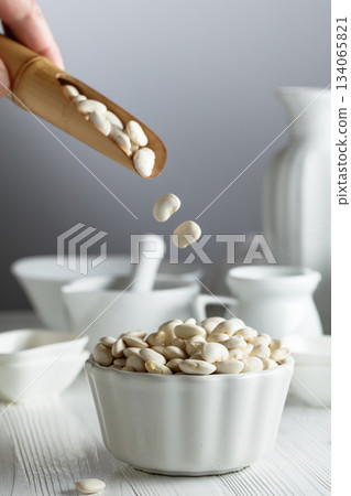 Dried white beans is poured in white bowl. Dried white beans is poured in white bowl. 134065821