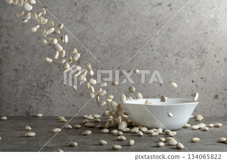 Dried white beans is poured in white ceramic bowl. Dried white beans is poured in white ceramic bowl. 134065822