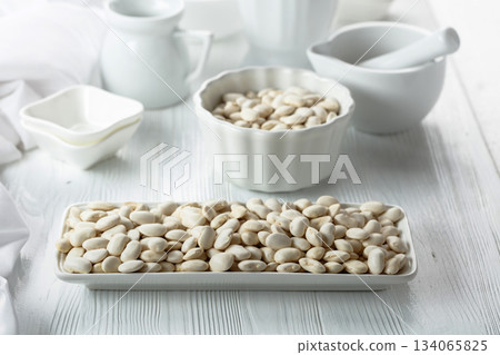 Dried white beans on a white table. Dried white beans on a white table. 134065825