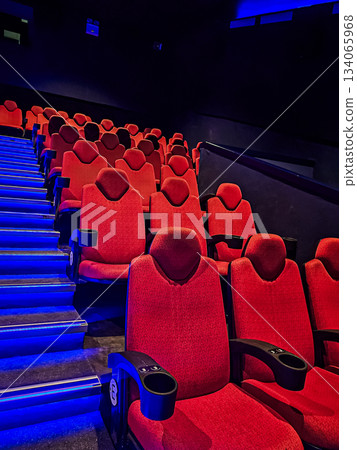 Photo showing half of a blue-lit staircase with red cinema seats alongside. The image highlights the theater interior, seating arrangement, and ambient lighting. 134065968