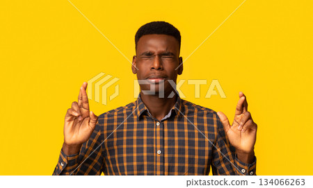 Making wish. Superstitious African American Guy Keeping His Fingers Crossed, Hoping For Luck, Pleading For Fortune, Standing With Closed Eyes Over Yellow Studio Background, Copy Space Making wish. Superstitious African American Guy Keeping His Fingers Crossed, Hoping For Luck, Pleading For Fortune, Standing With Closed Eyes Over Yellow Studio Background, Copy Space 134066263