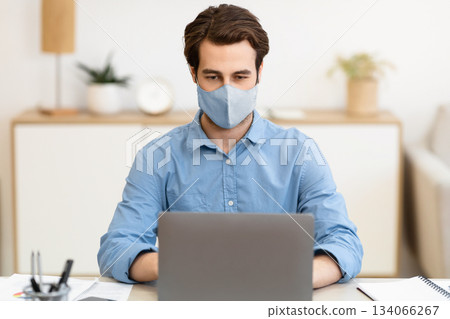 Businessman Wearing Face Mask Working On Laptop Computer Online Sitting At Workplace In Modern Office. Remote Work, Business And Entrepreneurship During Coronavirus Pandemic Concept Businessman Wearing Face Mask Working On Laptop Computer Online Sitting At Workplace In Modern Office. Remote Work, Business And Entrepreneurship During Coronavirus Pandemic Concept 134066267