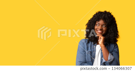 Curious african american young woman watching empty space for advertisement or announcement and smiling. Pretty curly black lady in jeans shirt looking at copy space over yellow background, panorama Curious african american young woman watching empty space for advertisement or announcement and smiling. Pretty curly black lady in jeans shirt looking at copy space over yellow background, panorama 134066307
