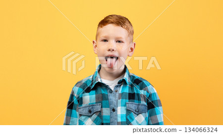 Spoiled ginger kid cute school boy in casual outfit showing his tongue at camera over yellow studio background, copy space. Spoiled child, kids behaviour problems concept Spoiled ginger kid cute school boy in casual outfit showing his tongue at camera over yellow studio background, copy space. Spoiled child, kids behaviour problems concept 134066324