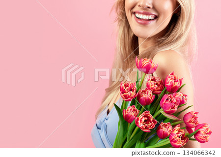 Cropped view of young lady with bouquet of lovely tulips on pink studio background, closeup. Unrecognizable millennial blonde holding flowers, enjoying her holiday gift, celebrating special occassion 134066342