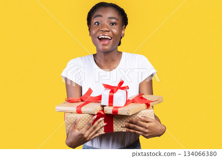 Excited Black Woman Holding Many Wrapped Gifts And Presents Boxes Smiling To Camera Posing Over Yellow Background In Studio. Holidays And Birthday, Christmas Celebration Concept Excited Black Woman Holding Many Wrapped Gifts And Presents Boxes Smiling To Camera Posing Over Yellow Background In Studio. Holidays And Birthday, Christmas Celebration Concept 134066380