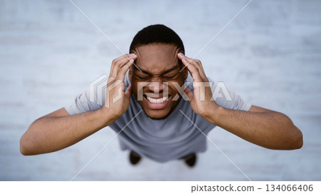 Top View Of Black Man Having Headache Suffering From Migraine Pain, Touching Aching Head Standing Indoors Over Gray Background. Male Health Problem Concept. Panorama, Selective Focus 134066406