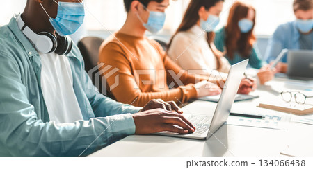 New Normal Reality Rules, People And Workspace Concept. Group of diverse international people wearing disposable surgical masks studying and working sitting at desk, preparing project, using laptop New Normal Reality Rules, People And Workspace Concept. Group of diverse international people wearing disposable surgical masks studying and working sitting at desk, preparing project, using laptop 134066438