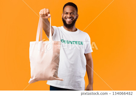 Stop Using Plastic. African Volunteer Man Showing White Eco Bag To Camera Posing Standing On Yellow Studio Background. Consumerism And Ecology, Plastic-Free Lifestyle 134066482