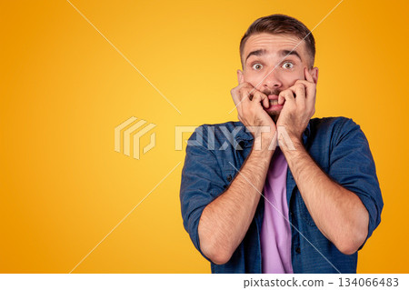 Scared Caucasian guy biting his nails in terror over grey studio background. Young man feeling terrified, suffering from fear or shock, having panic attack. Expressing negative emotions concept Scared Caucasian guy biting his nails in terror over grey studio background. Young man feeling terrified, suffering from fear or shock, having panic attack. Expressing negative emotions concept 134066483