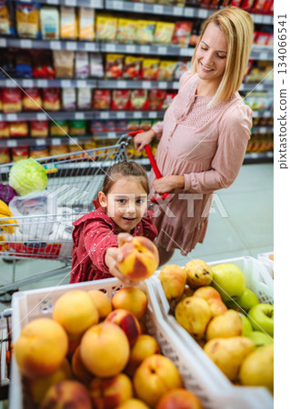 Mother and daughter picking fresh fruits at grocery store 134066541
