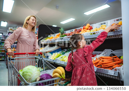 Mother and daughter picking fresh fruit in supermarket 134066550