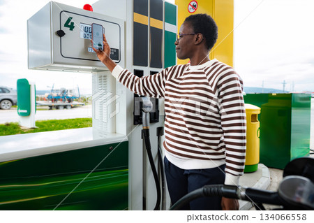 Woman paying for gas using smartphone outside 134066558