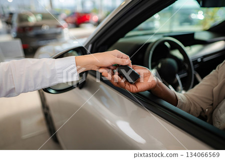 Car salesperson handing over car key to customer Car salesperson handing over car key to customer 134066569