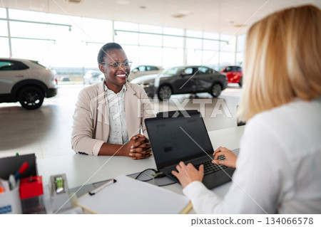 Happy customer talking to saleswoman at car dealership Happy customer talking to saleswoman at car dealership 134066578