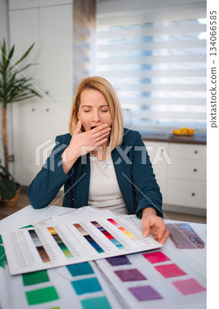 Tired designer yawning feeling burnout while working with color swatches Tired designer yawning feeling burnout while working with color swatches 134066585