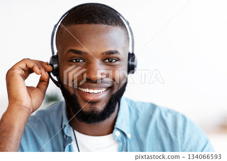 Call Center Operator. Closeup shot of friendly black man hotline manager in headset, portrait of handsome african american customer service representative looking at camera and smiling, free space Call Center Operator. Closeup shot of friendly black man hotline manager in headset, portrait of handsome african american customer service representative looking at camera and smiling, free space 134066593