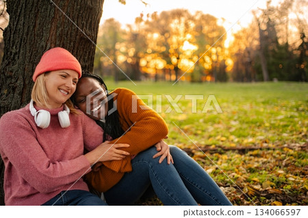 Diverse women friends laughing together in autumn park Diverse women friends laughing together in autumn park 134066597