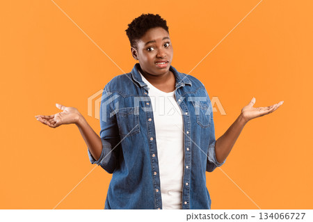 I Don't Know. Puzzled Plus-Size Black Woman Shrugging Shoulders Standing Posing Over Yellow Studio Background, Looking At Camera. Shoulder Shrug Gesture Concept. I Don't Know. Puzzled Plus-Size Black Woman Shrugging Shoulders Standing Posing Over Yellow Studio Background, Looking At Camera. Shoulder Shrug Gesture Concept. 134066727