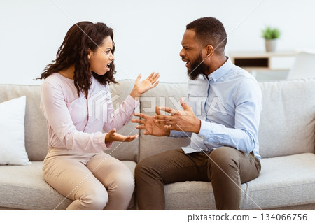 Angry millennial black couple shouting and blaming each other, frustrated stressed husband and annoyed wife quarreling about bad relationship, unhappy young family arguing and fighting at home concept 134066756