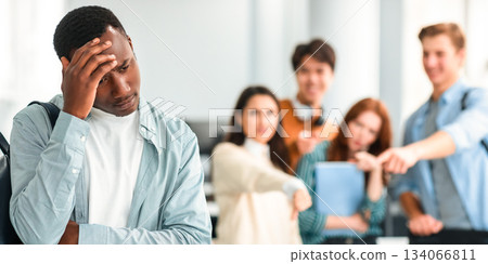 Bullying Concept. Rude diverse group of people mocking and making fun of sad african american guy, pointing fingers at him and laughing, standing in blurred background. Prank, abuse, public disgrace Bullying Concept. Rude diverse group of people mocking and making fun of sad african american guy, pointing fingers at him and laughing, standing in blurred background. Prank, abuse, public disgrace 134066811