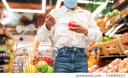 African American Woman Doing Grocery Shopping Buying Fresh Vegetables In Supermarket, Walking With Basket Full Of Food, Wearing Face Mask. Female Buyer In Groceries Store. Cropped, Selective Focus 134066833
