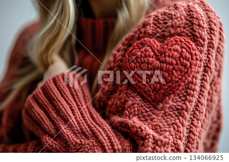 Cozy Night In. Red heart pattern is crochet on a modern sweater. Creative hobby. Valentines Day concept. 134066925