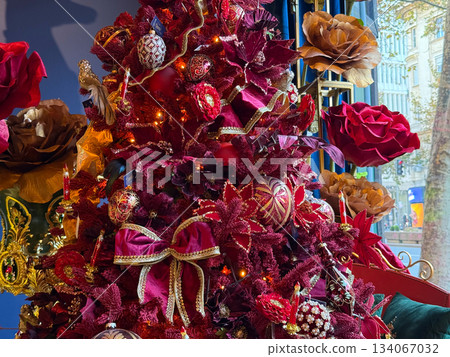 Luxurious burgundy Christmas tree richly decorated with flowers, bows and gold ornaments near window view. Festive opulence, elegant holiday atmosphere, warm seasonal celebration spirit and rich Luxurious burgundy Christmas tree richly decorated with flowers, bows and gold ornaments near window view. Festive opulence, elegant holiday atmosphere, warm seasonal celebration spirit and rich 134067032