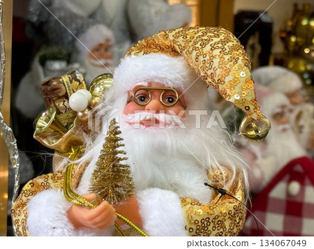 Golden Santa figurine holding miniature Christmas tree and festive gifts Golden Santa figurine holding miniature Christmas tree and festive gifts 134067049