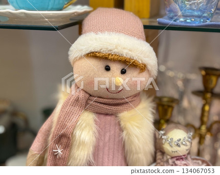 Christmas Soft fabric doll in pink winter clothing with hat and scarf on the shelf Christmas Soft fabric doll in pink winter clothing with hat and scarf on the shelf 134067053