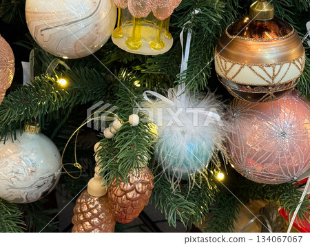 Festive combination of baubles, pinecones and fluffy ornaments placed on a decorated Christmas tree. 134067067