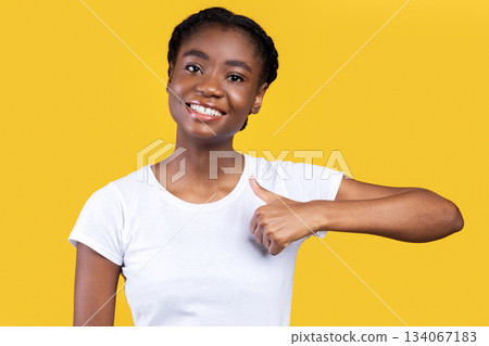 Black Young Lady Gesturing Thumbs Up Smiling To Camera Posing Standing Over Yellow Background In Studio. I Like It, Thumbs-Up Gesture Concept. Woman Showing Thumbs In Approval 134067183