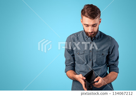 Poverty and unemployment concept. Desperate young man showing empty wallet with no money over blue studio background. Millennial guy losing his job or business during economic crisis Poverty and unemployment concept. Desperate young man showing empty wallet with no money over blue studio background. Millennial guy losing his job or business during economic crisis 134067212