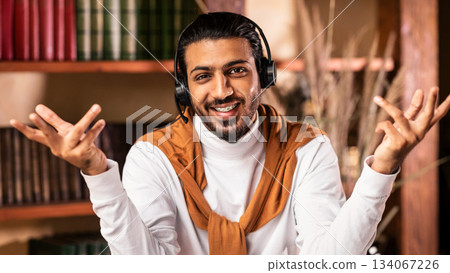 Smiling Arab Teacher Guy Talking To Camera Teaching Online Wearing Headphones Having Distance Class Sitting At Home. Remote Education, Distant Teaching And Learning Concept Smiling Arab Teacher Guy Talking To Camera Teaching Online Wearing Headphones Having Distance Class Sitting At Home. Remote Education, Distant Teaching And Learning Concept 134067226